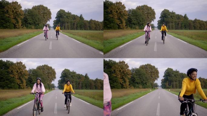 两名成年成年女性的静态手持照片，在高速公路上快乐地骑行，以慢动作穿过相机旁边