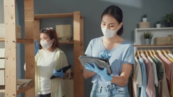 专业迷人开朗的两个亚洲女士老板青少年与休闲手术口罩保持平板电脑检查库存产品控制交付货物客户订单准备新