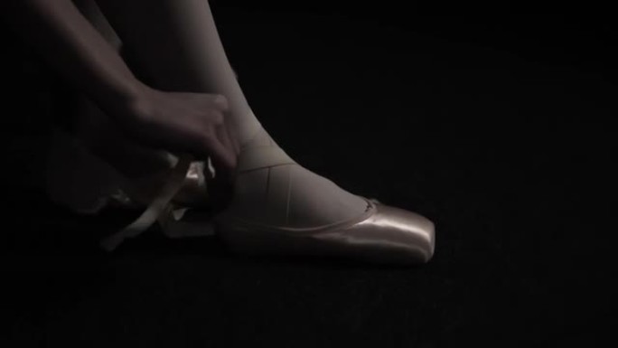 年轻的芭蕾舞女舞者在工作室穿上脚尖鞋