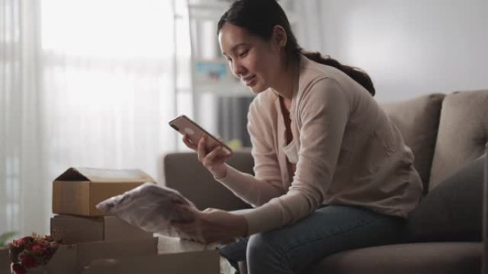 亚洲女性从网上商店开箱订购并在移动购物应用程序上拍照以进行评论