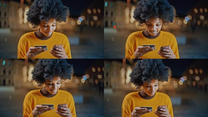 年轻的黑人妇女使用她的信用卡在智能手机上进行在线支付