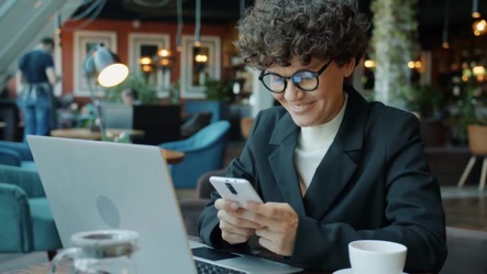 快乐的商务女士使用智能手机触摸屏，在咖啡馆享受在线交流和社交媒体。