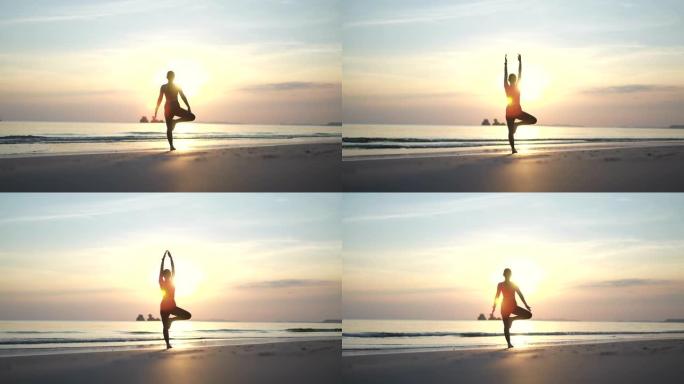 在海滩上做瑜伽的运动女人的剪影