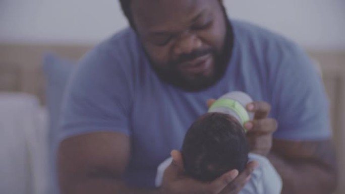 年轻的父亲用奶瓶喂养他的男婴儿子