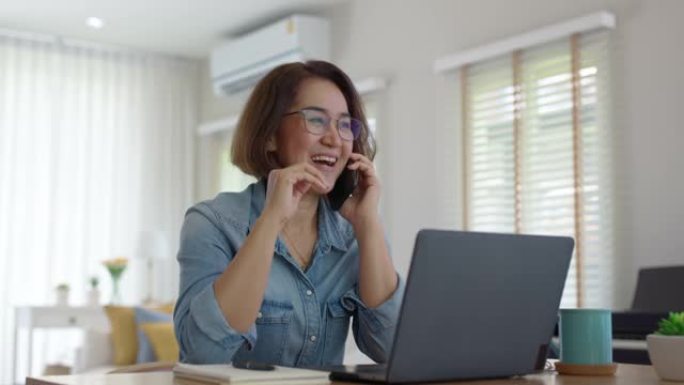 亚洲成熟成年女性在手机上通话在家快乐工作。