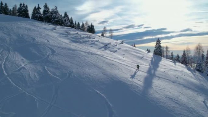 空中: 巡回滑雪者爬上雪峰以打开新鲜的粉末雪