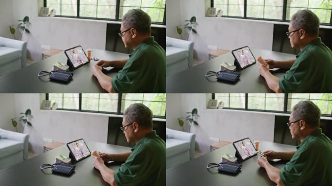 高级成年男子在数字平板电脑上与女医生在家里的客厅进行远程视频通话远程医疗会议
