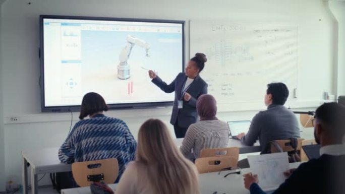 大学机器人技术讲座班: 黑人老师向学生讲解工程学。她使用白板。各种各样的年轻工程师聆听有关机械臂使用