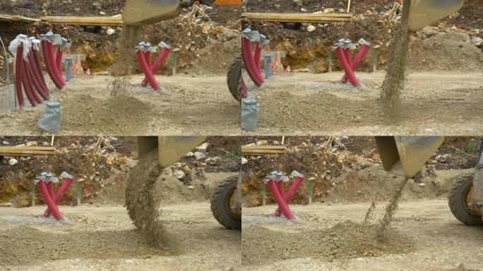 特写: 推土机在混凝土板浇筑前倾倒一个装满岩石的桶。
