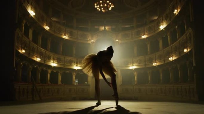 一位年轻优美的古典芭蕾舞女舞者穿着白色芭蕾舞短裙的电影镜头正在热身，在演出开始前在经典剧院舞台上表演