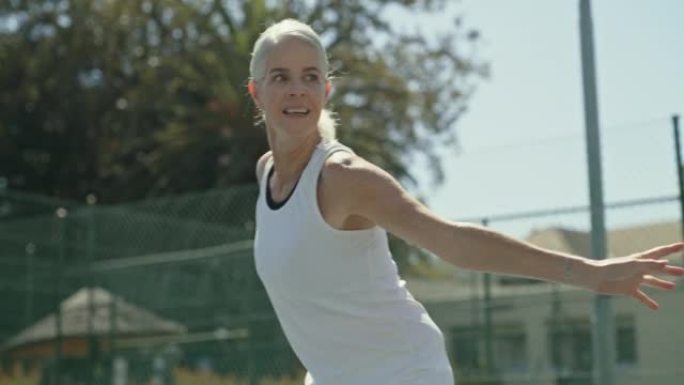 一个健康的成熟女人在比赛中挥舞网球拍击球