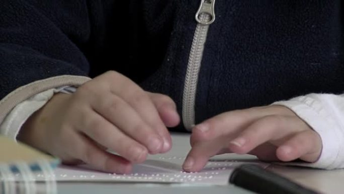 在阿根廷的一所公立学校为盲人和视障儿童学习使用盲文字母的孩子的手。特写。