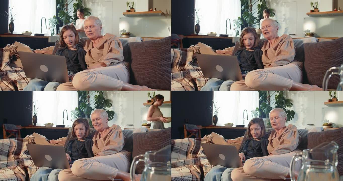 在线安全。可爱的少女教老奶奶安全地坐在舒适的家庭沙发上使用笔记本电脑和互联网。