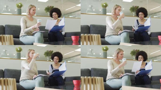 多元化的女同事坐在沙发上，喝咖啡，在办公室里谈生意