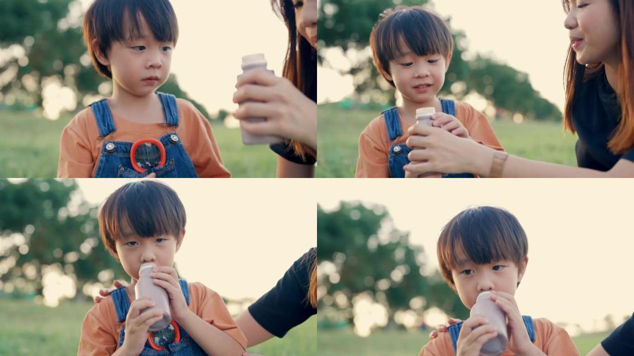 饥饿的男孩在家庭野餐时喝牛奶。