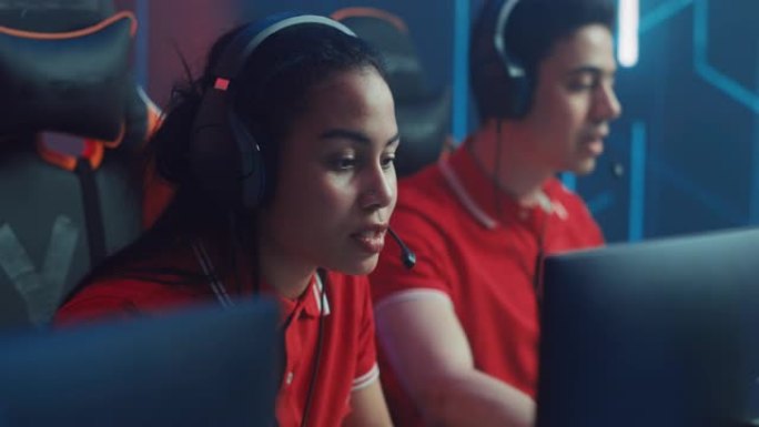 职业女孩玩电脑视频游戏，与队友在锦标赛上与头戴式耳机交谈。在网络游戏竞技场玩的多样化的电子竞技游戏团