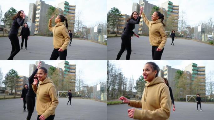 女子足球运动员向朋友击掌并在城市运动场庆祝进球