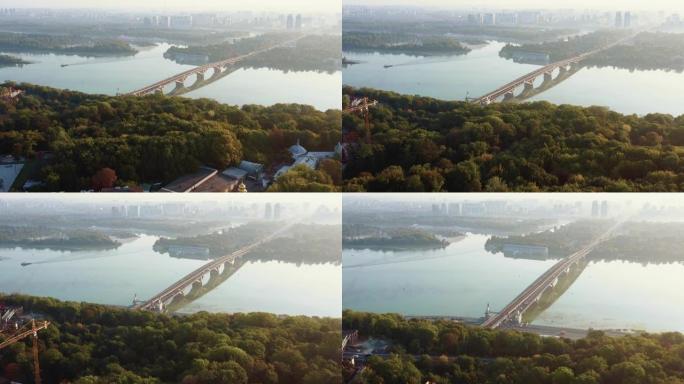 无人机在靠近大教堂建筑顶部的地方飞向乌克兰基辅第聂伯河上美丽的宁静日出桥