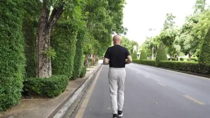 后视亚洲老年人锻炼。高级男子在公园的道路上奔跑