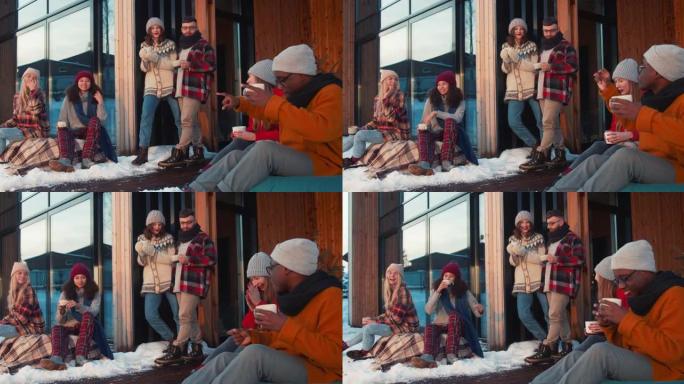 一起寒假。一群快乐的朋友在舒适的新年假期小屋露台上喝茶聊天慢动作