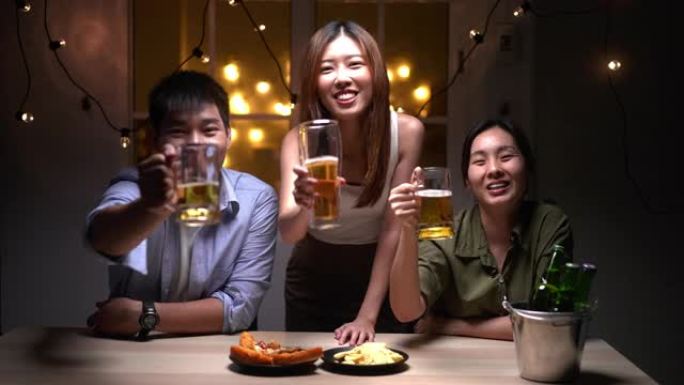 一群亚洲朋友的人使用手机在视频聊天中问候朋友，喝啤酒和晚上参加聚会