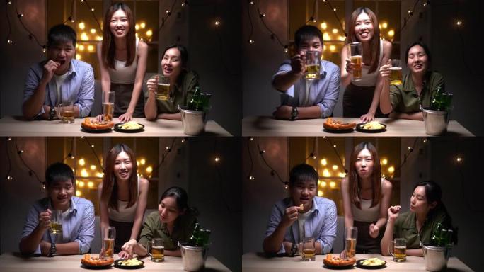 一群亚洲朋友的人使用手机在视频聊天中问候朋友，喝啤酒和晚上参加聚会
