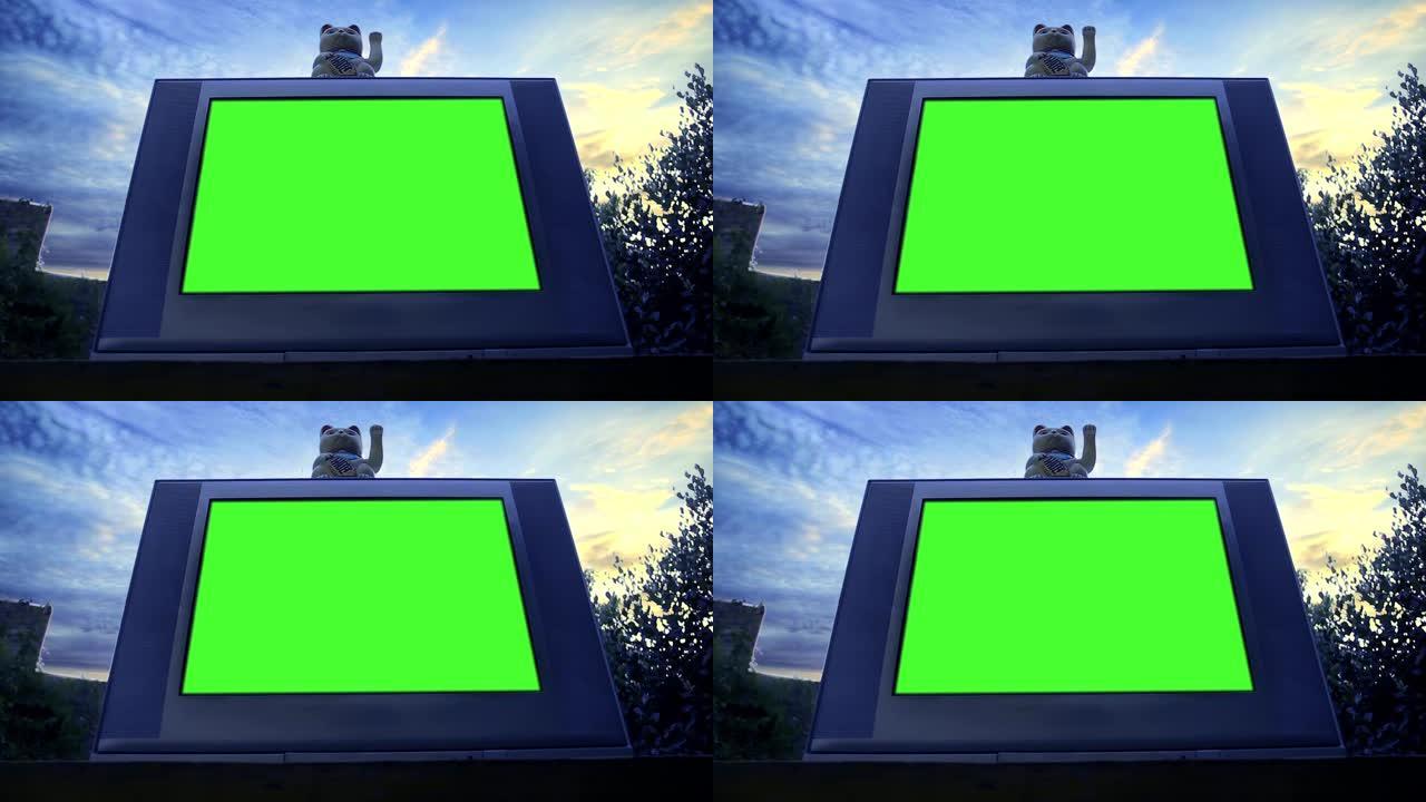 Maneki Neko猫和绿屏旧电视。低角度视图。