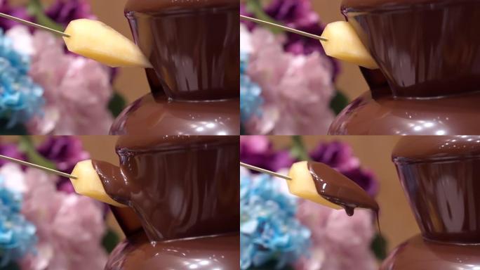 4K UHD慢动作: 将哈密瓜甜瓜浸入巧克力喷泉中。