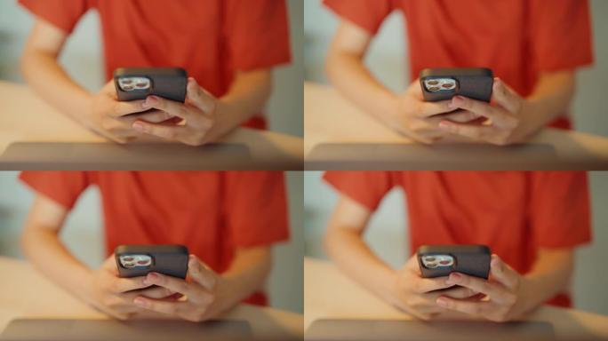 年轻的亚洲女孩使用智能手机在家庭办公室的桌子上检查互联网上的社交媒体