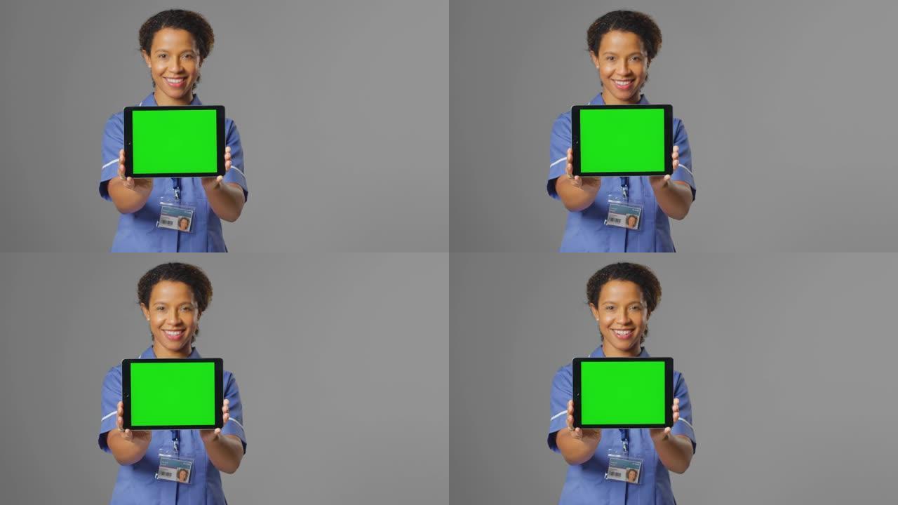 微笑护士穿着制服拿着数码平板电脑空白绿屏的肖像