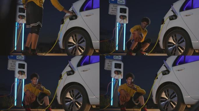 篮球运动员在将电动汽车插头插入汽车充电时使用智能手机