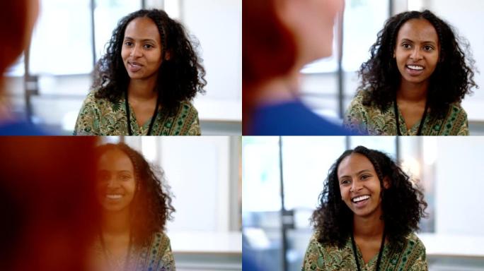 微笑的非洲妇女在办公室与同事交谈