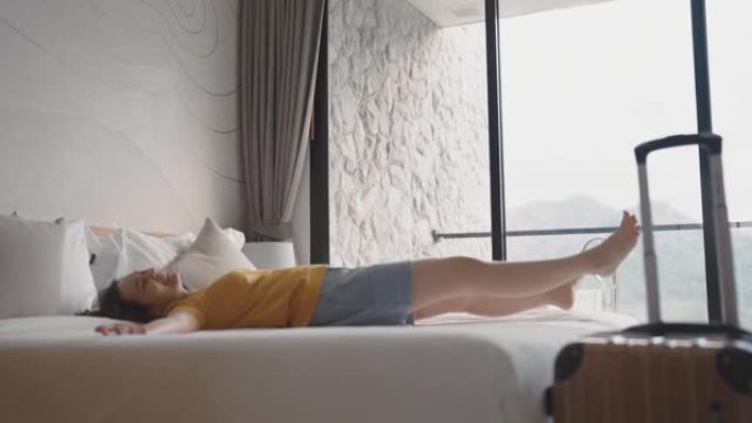 亚洲妇女在酒店房间的床上摔倒