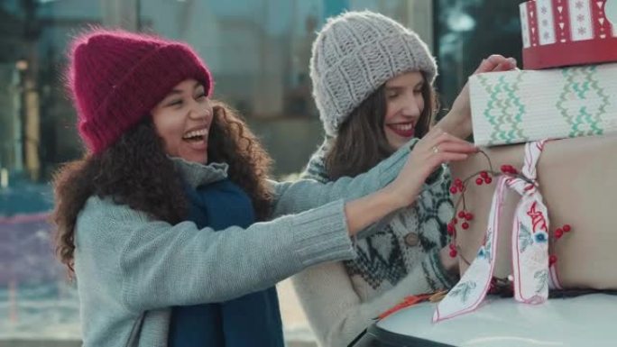 两个戴着帽子的年轻快乐美丽多样的女性朋友把圣诞礼物放在外面微笑慢动作的车顶。