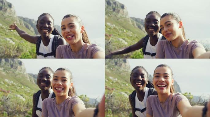 两个女朋友在户外登山时自拍。快乐的女人微笑着笑，同时在背景中拍摄自然景观。保持健康并保持活跃