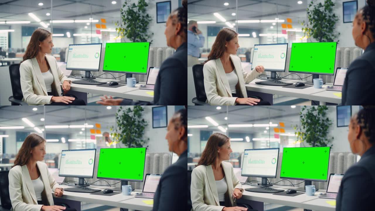 两名女同事在现代商务办公室使用绿屏模拟显示的计算机上工作时，彼此亲切地交谈，笑着笑。经理和员工讨论一