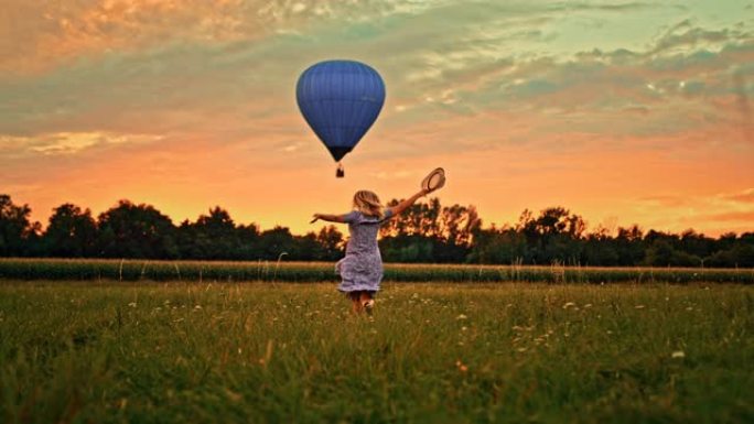 超级慢动作女人在草地上奔向飞行的热气球