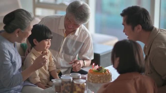 亚洲华人多代家庭拍手唱生日歌为6岁男孩在客厅庆祝生日