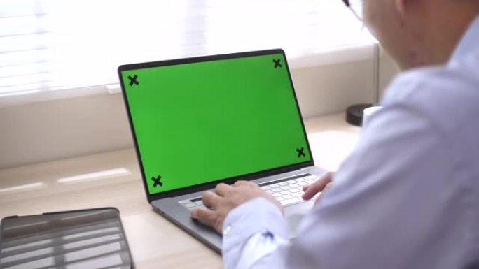 男人在办公室使用带有绿屏的笔记本电脑