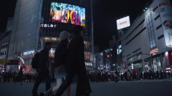 行人在东京涩谷十字路口过马路。拥挤的人和游客穿越道路，并在涩谷争先恐后的十字路口拍照。交通汽车和跨交