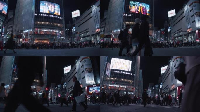 行人在东京涩谷十字路口过马路。拥挤的人和游客穿越道路，并在涩谷争先恐后的十字路口拍照。交通汽车和跨交