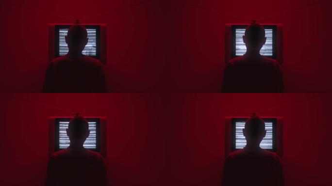 一个男人在电视前的轮廓，在黑暗的房间里的框架中间有电视静电噪音