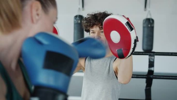 女子拳击教练的慢动作激励运动员一起在健身房练习
