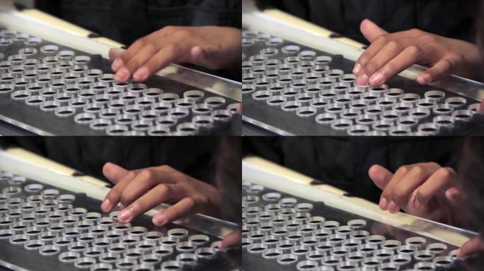 在课堂上的计算机课程中，一名视力障碍的男高中生的手触摸了计算机键盘。特写。