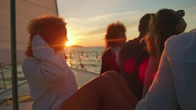 SLO MO一群朋友在日落时航行时，在帆船甲板上享受微风