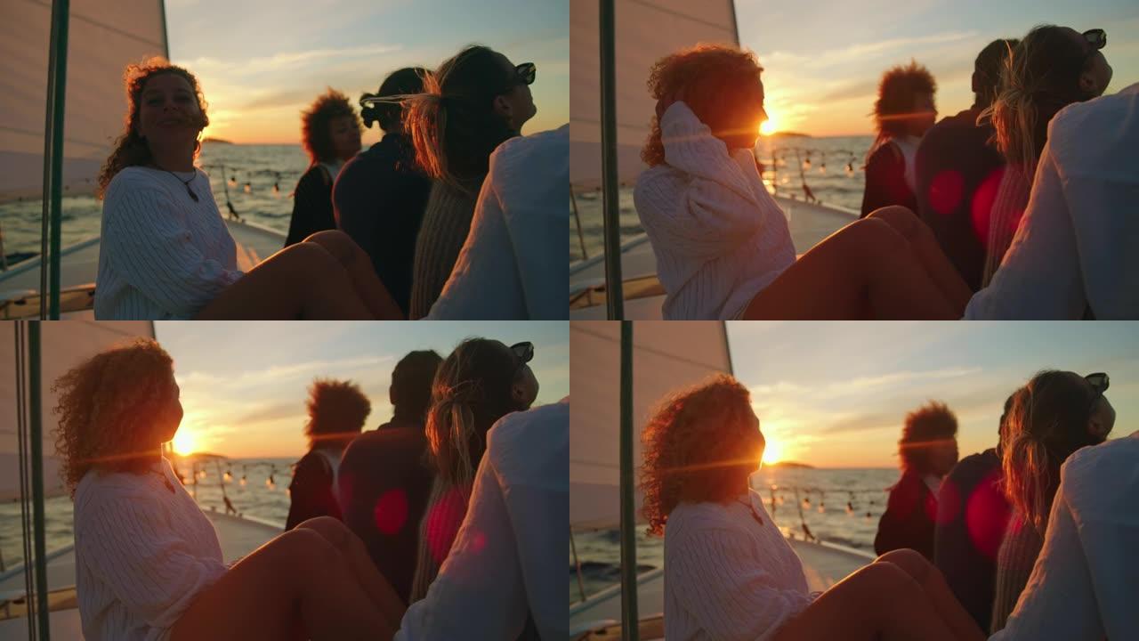 SLO MO一群朋友在日落时航行时，在帆船甲板上享受微风