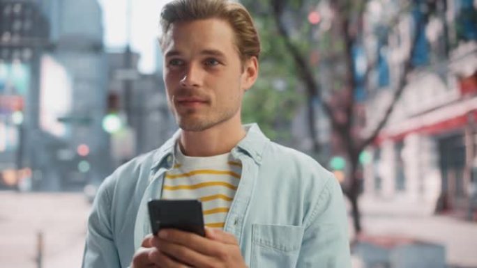 一个英俊的年轻人穿着便服，在城市街道上使用智能手机的肖像。大城市的经理与人们在线联系，消息传递和浏览
