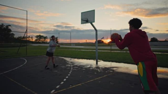 SLO MO两个十几岁的男孩在日落时打篮球