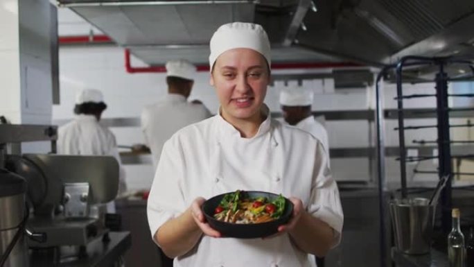高加索女厨师的肖像展示菜肴并看着相机