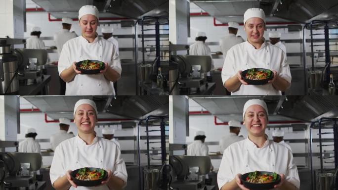 高加索女厨师的肖像展示菜肴并看着相机
